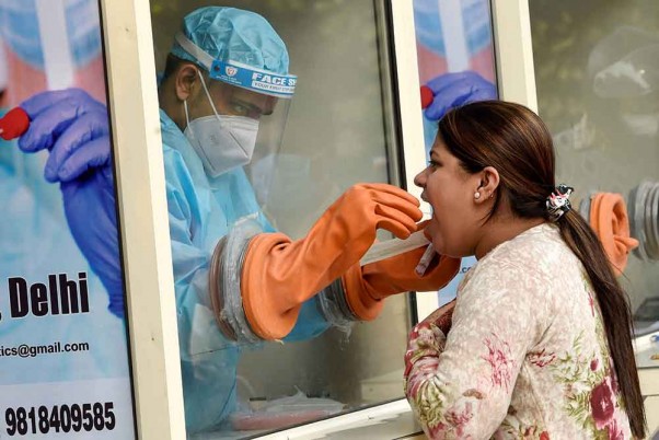 राजधानी दिल्ली के आईआईटी दिल्ली में कोविड-19 परीक्षण के लिए स्वाब नमूना एकत्र करता एक स्वास्थ्य कार्यकर्ता