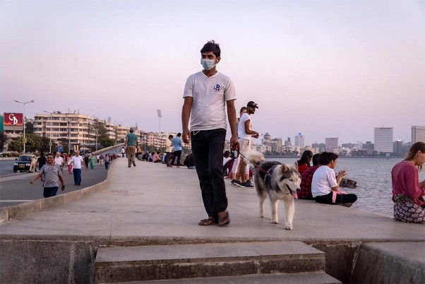 कोरोना वायरस के प्रकोप के मद्देनजर एहतियात के तौर पर मुंबई के मरीन ड्राइव पर मास्क पहने वॉक करता युवक
