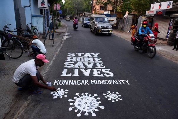 कोरोनावायरस महामारी को रोकने के लिए लगाए गए लॉकडाउन के बीच कोलकाता में कोविड-19 के बारे में जागरूकता बढ़ाने के लिए सड़क पर चित्रकारी करता एक कलाकार