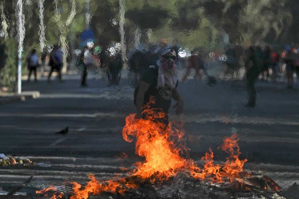 चिली के सैंटियागो में पुलिस के साथ झड़प के दौरान मोर्चाबंदी करते सरकार विरोधी प्रदर्शनकारी