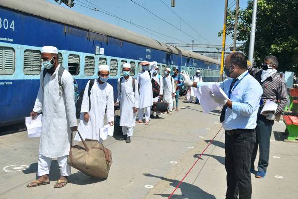 मुरादाबाद में लॉकडाउन के दौरान बिहार के लिए एक विशेष ट्रेन में चढ़ने से पहले प्रवासियों के दस्तावेजों की जांच करता रेलवे अधिकारी
