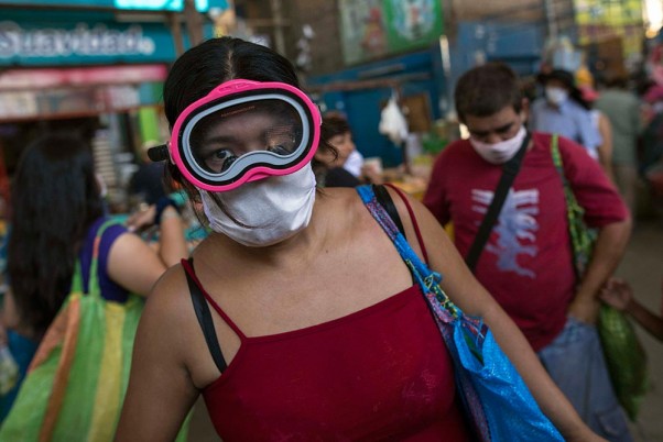 कोरोना वायरस के बढ़ते मामलों के बीच पेरू के लीमा में एहतियात के तौर स्कूबा और सर्जिकल मास्क पहनी महिला