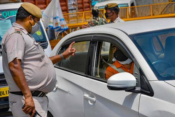 लॉकडाउन के दौरान दिल्ली-गाजीपुर सीमा पर वैध दस्तावेजों के लिए यात्रियों से पूछताछ करते पुलिसकर्मी