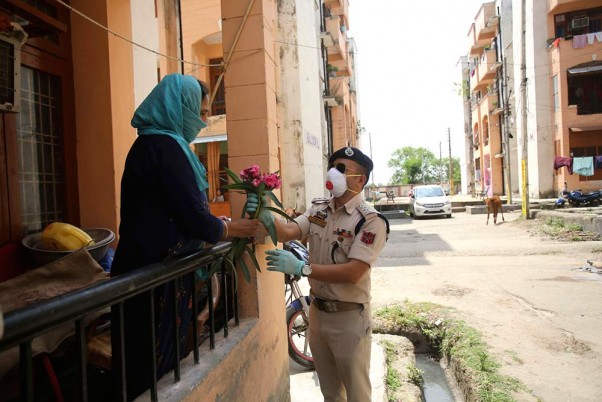 जम्मू में लॉकडाउन के आदेशों का पालन करने के लिए स्थानीय लोगों को फूल देकर धन्यवाद देता एक पुलिस अधिकारी