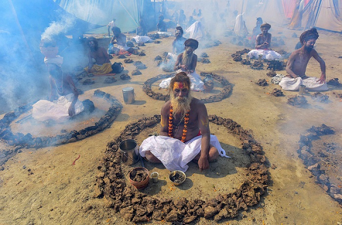 प्रयागराज में चल रहे कुंभ के दौरान धूनी जलाकर अनुष्ठान करते साधु