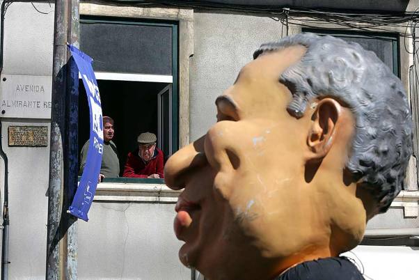 मजदूर यूनियन द्वारा लिस्बन में आयोजित मई दिवस प्रदर्शन के दौरान पुर्तगाल के प्रधानमंत्री एंटोनियो कोस्टा की तरह दिखने वाली एक विशालकाय कठपुतली को देखते लोग