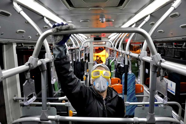 ईरान के तेहरान में कोरोना वायरस के मद्देनजर एक सार्वजनिक बस में सफाई करता कार्यकर्ता