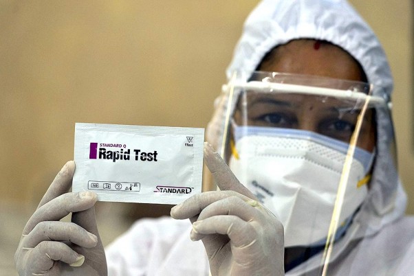 राजधानी दिल्ली के सरकारी स्कूल में एक परीक्षण केंद्र पर कोविड-19 टेस्ट के लिए रैपिड टेस्ट किट दिखाती स्वास्थ्यकर्मी