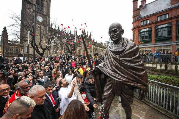 ब्रिटेन के शहर मैनचेस्टर के लिए एक उपहार के रूप में महात्मा गांधी की एक नई प्रतिमा का धूमधाम से अनावरण करते लोग