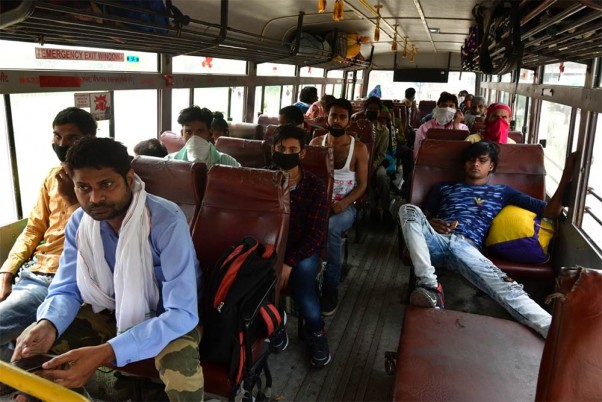 दिल्ली के आनंद विहार में लॉकडाउन 5.0 के बीच फिर से शुरू की गई सेवाओं के दौरान यूपीएसआरटीसी बस से यात्रा करते लोग
