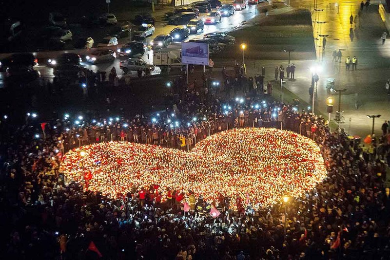 पोलैंड में ग्दान्स्क पावेल एडमोविक के राष्ट्रपति को श्रद्धांजलि देने के लिए मोमबत्तियों के साथ दिल के आकार में खड़े हुए लोग