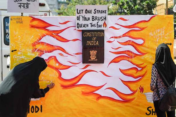 मुंबई में नागरिकता संशोधन अधिनियम (सीएए) के प्रदर्शन के दौरान दीवार पर लिखते प्रदर्शनकारी