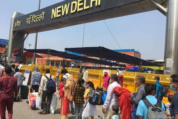 भारतीय रेलवे द्वारा नई दिल्ली से 200 यात्री ट्रेनों का परिचालन फिर से शुरू किए जाने के बाद नई दिल्ली रेलवे स्टेशन में प्रवेश करने के लिए कतार में प्रतीक्षा करते यात्री
