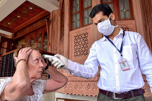 बीकानेर के एक होटल में कोरोना वायरस के प्रकोप के मद्देनजर एहतियात के तौर पर पर्यटक की स्क्रीनिंग करता डॉक्टर