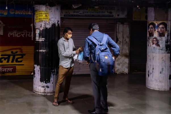 मुंबई के छत्रपति शिवाजी टर्मिनस में फेस मास्क बेचता एक स्ट्रीट वेंडर