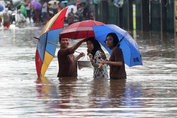 इंडोनेशिया में जकार्ता के बाहरी इलाके में बाढ़ के दौरान लोग