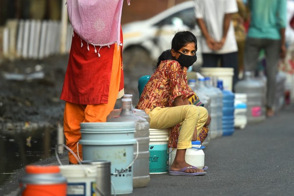 नई दिल्ली के मयूर विहार में मास्क पहनकर टैंकर से पीने का पानी लेने का इंतजार करती महिलाएं
