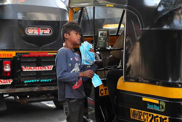 कोरोना वायरस के प्रकोप के मद्देनजर मुंबई के ट्रैफिक चौराहे पर मास्क बेचता एक किशोर