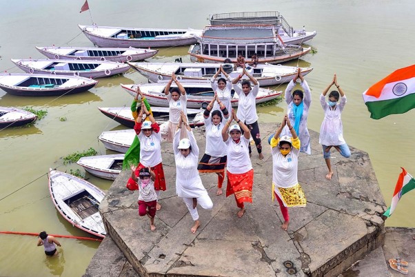 वाराणसी में अंतरराष्ट्रीय योग दिवस से पहले गंगा घाट पर योग करते लोग