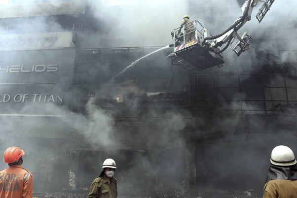 नई दिल्ली के लाजपत नगर स्थित सेंट्रल मार्केट के एक शोरूम में आग बुझाने का प्रयास करते दमकलकर्मी
