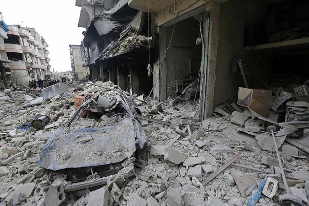 सीरिया के इदलिब प्रांत के अरिहा शहर पर हवाई हमले के बाद क्षतिग्रस्त स्थल का निरीक्षण करते लोग