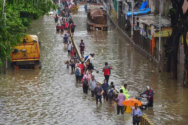 मुंबई के दादर में भारी बारिश के बाद जलभराव वाली सड़क से गुजरने के लिए लोग मजबूर