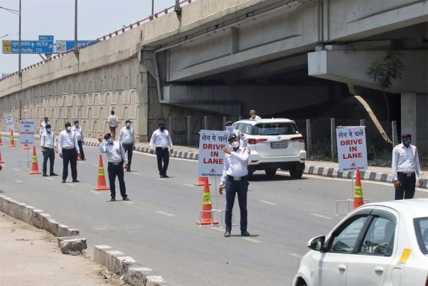 नई दिल्ली के गाजीपुर में यात्रियों को लाइन में चलने का निर्देश देते ट्रैफिक पुलिसकर्मी