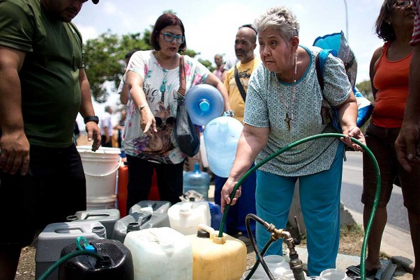 57 साल की मारिया रोजास, वेनेजुएला के काराकस में कंटेनर में पानी भरती हुई। वेनेजुएला में इस वक्त तेल सस्ता है और पानी महंगा है।