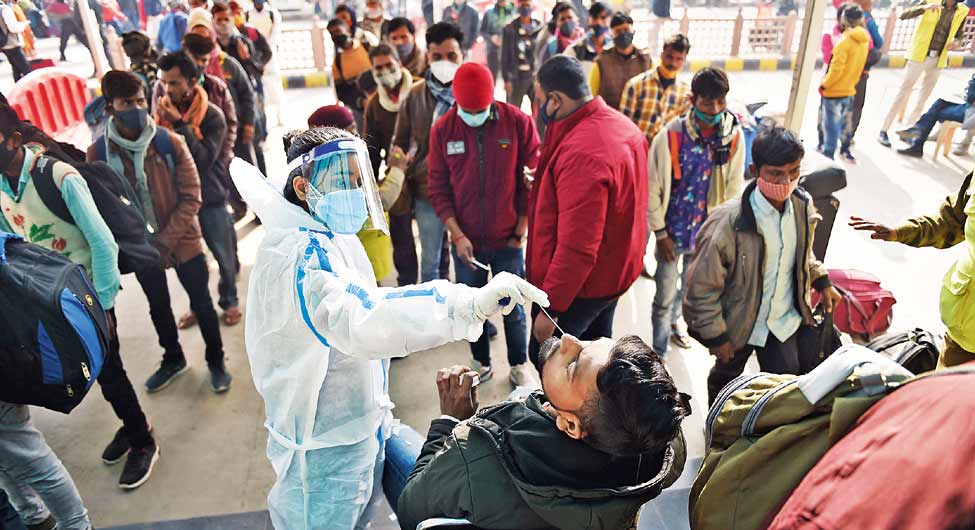 दिल्ली के आनंद विहार रेलवे स्टेशन पर आने वाले यात्रियों का ओमिक्रॉन टेस्ट के लिए नमूना लेते स्वास्थ्य कर्मी