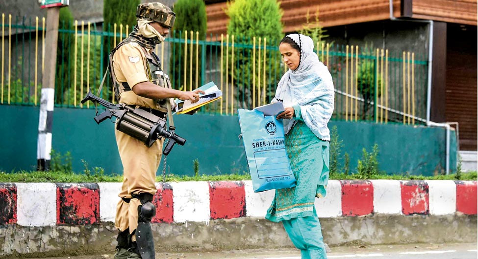पाबंदी के बीचः श्रीनगर में एक महिला अस्पताल जाने के लिए कागजात दिखाती हुई