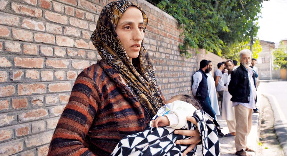 अपनों की तलाश मेः 45 दिन की अपनी बच्ची को लेकर श्रीनगर के एक थाने के बाहर पति की तलाश में खड़ी कश्मीरी महिला