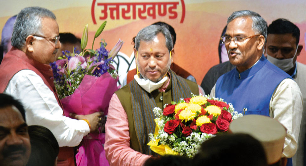 नए मुख्यमंत्री तीरथ सिंह को गुलदस्ता भेंट करते त्रिवेंद्र सिंह रावत