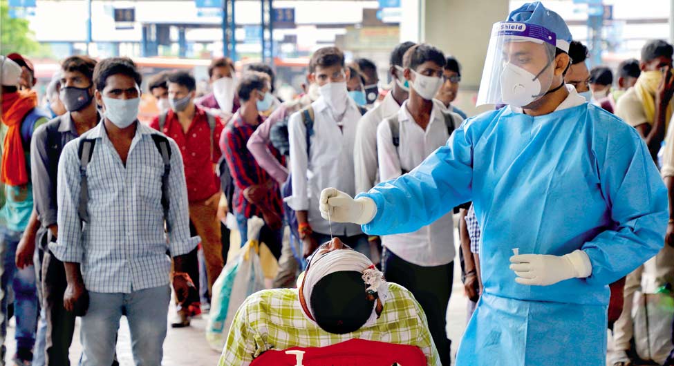 जांच में भी तेजी जरूरीः दिल्ली में प्रवासी मजदूरों की टेस्टिंग करता स्वास्थ्यकर्मी