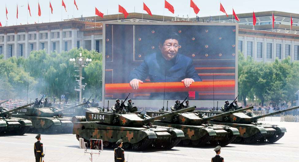 आक्रामक रुखः बीजिंग के थ्यान अन मन चौक पर सैन्यत परेड के दौरान गुजरते टैंक और स्क्रीन पर दिखते चीन के राष्ट्रपति जिनपिंग
